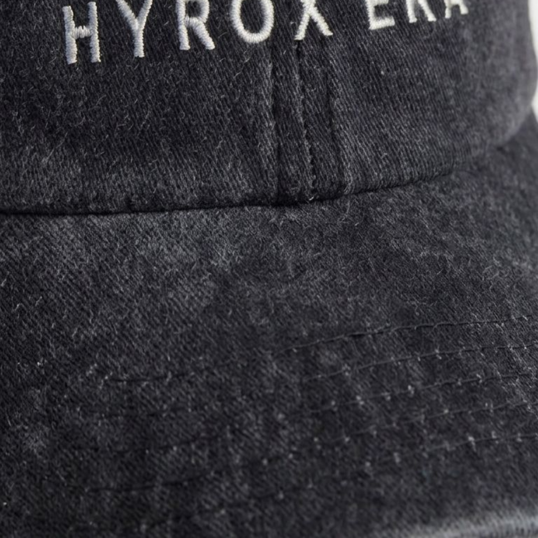 Close-up of black washed cap fabric and off-white embroidery detail