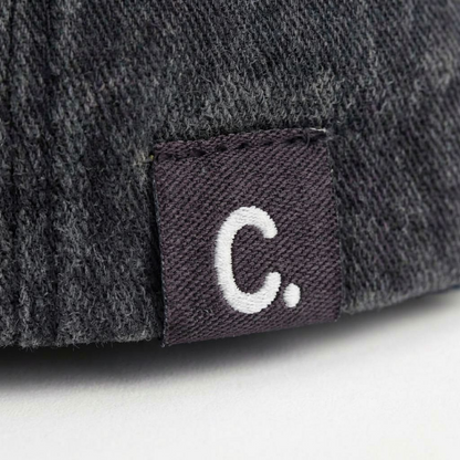 Close-up of black washed cap fabric and off-white embroidery detail